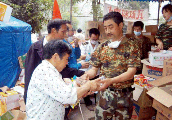 5月24日，党员、北川羌族自治县民政局局长王洪发（右三）为灾区群众分发食 品。地震夺去王洪发包括16岁儿子在内的20位亲人的性命，而他却用自己的双手刨出 10条生命（CFP 提供）.PNG